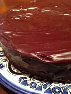 a chocolate cake sitting on top of a blue and white plate covered in frosting