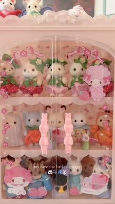 there are many small stuffed animals on the shelf in this toy display case with pink bows