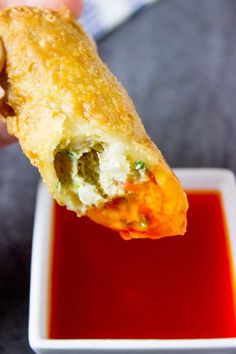 a piece of food that is being held up in the air over a bowl of ketchup