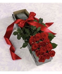 a bouquet of red roses in a box with a ribbon on the top and bottom