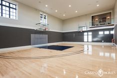 an indoor basketball court with hard wood flooring and high ceiling lighting is seen in this image