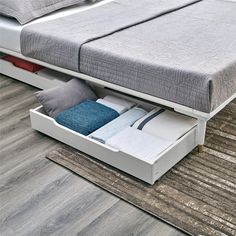 a bed with two drawers underneath it on top of a carpeted floor next to a rug