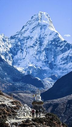 the mountain is covered in snow and has people walking up to it on a trail