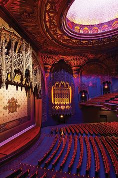 an auditorium with rows of seats and a ceiling that has intricate designs on the walls