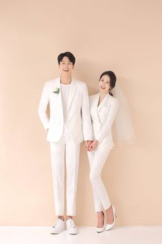 two people standing next to each other in white outfits