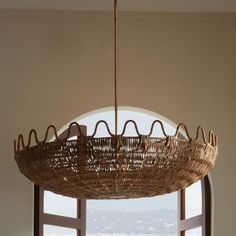 a wicker chandelier hanging from the ceiling in front of a window with an open door