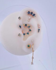 a pair of earring that has been placed on top of a white object with blue and green stones