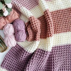 a crocheted blanket next to yarn and flowers