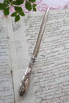 an old letter with writing on it next to a pen and leafy green plant