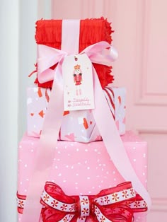 a stack of wrapped presents on top of each other in pink and red with bows