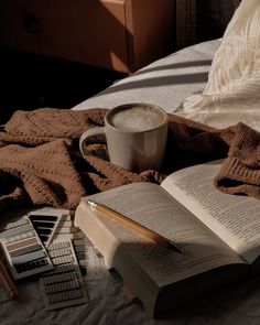 an open book, calculator and cup of coffee on a bed with blankets