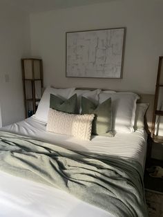 a bed with white sheets and green pillows