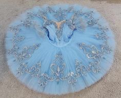 a blue ball gown with silver sequins on the top and bottom, sitting on carpet