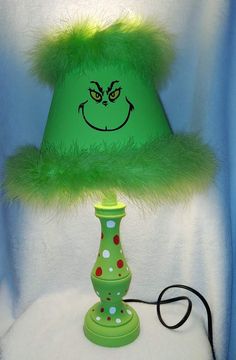 a green lamp with a smiling face on it's side and a fuzzy green shade