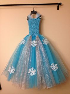 a dress hanging on a wall with snowflakes all over it and blue tulle