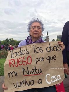 an older woman holding a sign in spanish