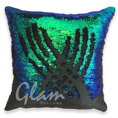 a green and blue sequinized pillow with palm trees on the front, which is black