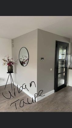 an empty room with a door and mirror on the wall, in front of a kitchen