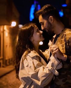 a man and woman standing next to each other in front of a building at night