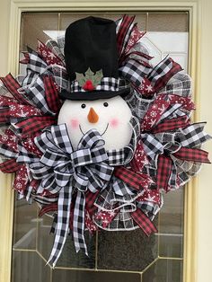 a snowman wreath with a black top hat and plaid bow on the front door