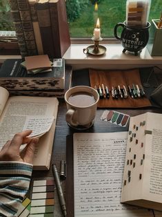 a person sitting at a table with books, coffee cup and pen in front of them