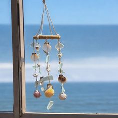 seashells hanging from a window sill with the ocean in the background