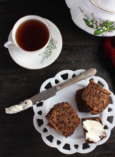 three pieces of cake on a white plate next to a cup of tea