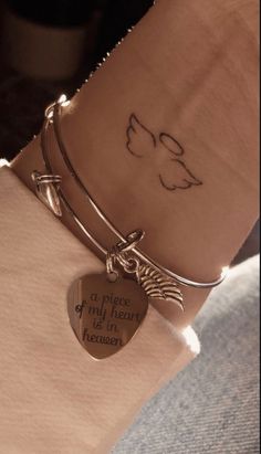 a woman's arm with a heart shaped charm and a quote on the wrist