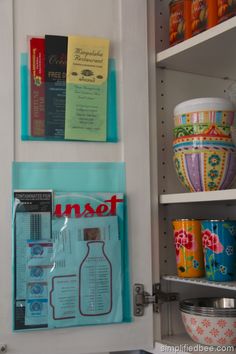 there are many cups on the shelves in this kitchen cabinet and one is filled with books