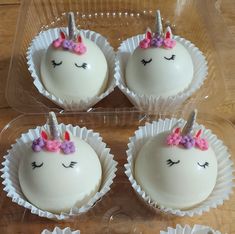 four cupcakes with white frosting and pink bows on them in plastic cups