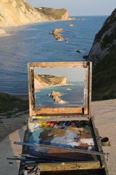 an easel with some paint on it near the ocean