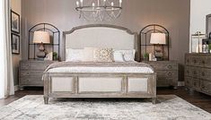 a large bed sitting in a bedroom next to two dressers and a chandelier