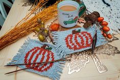 a cup of coffee sitting on top of a wooden table next to some knitting needles