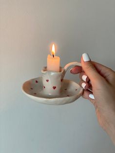 a person holding a tea cup with a candle in it and a saucer on the side