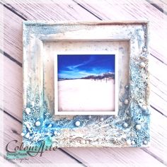 an old photo frame is sitting on a wooden table with shells and seaweed around it