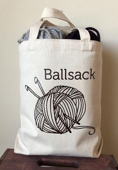 a ball of yarn sitting on top of a wooden table next to a white bag