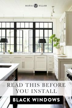 a large kitchen with white cabinets and black windows