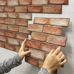 two hands are placing bricks on the wall to make it look like they have been painted