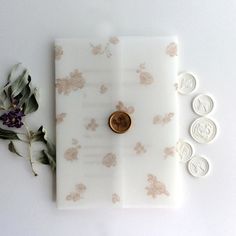 a button is sitting on top of a white paper with flowers and leaves around it