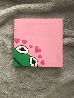 a painting of a green frog with hearts on it's chest and eyes painted on pink paper