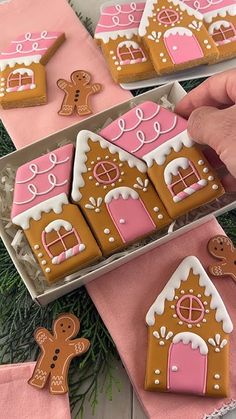 gingerbread cookies decorated with pink and brown icing are being held by someone's hand