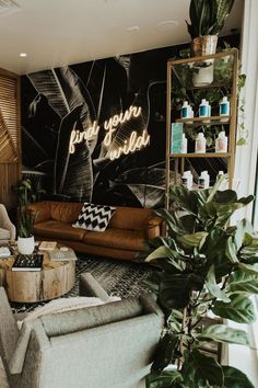 a living room filled with furniture and lots of greenery next to a large wall