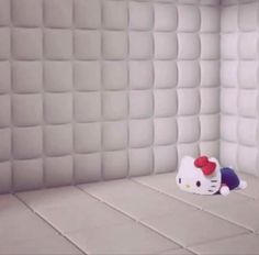 a hello kitty stuffed animal laying on top of a bed in a room with white walls