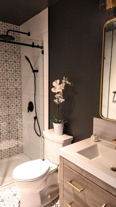 a white toilet sitting next to a sink in a bathroom under a mirror and shower