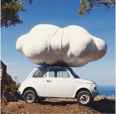 a white car with two large rocks on top of it's roof, parked in front of the ocean