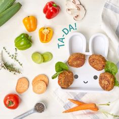 a plate with some food on it next to carrots, peppers and broccoli