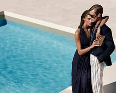 a man and woman standing next to each other near a swimming pool with their arms around each other