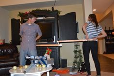 a man and woman standing in a living room holding a tape measure with their hands