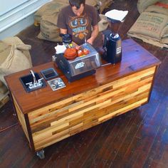 a young man is making something at his coffee shop counter made out of pallet wood