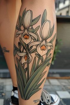 a woman's legs with tattoos on them and flowers in the middle of her leg